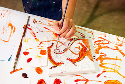 Closeup of a young campers hand as they work on a painting