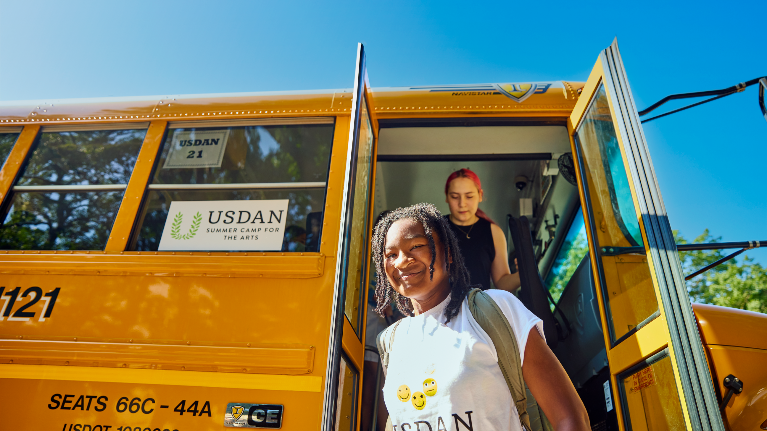 Student walking off the bus and smiling