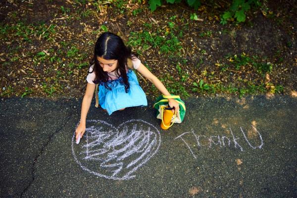 Student drawing "Thank U" in chalk