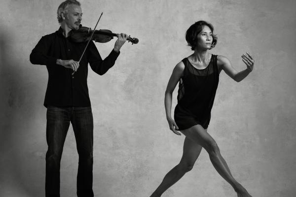 Black and white photo of Colin Jacobsen emotionally playing the violin and Maile Okamura mid-movement