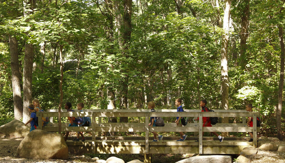 Young kids walking with a counselor over a bridge