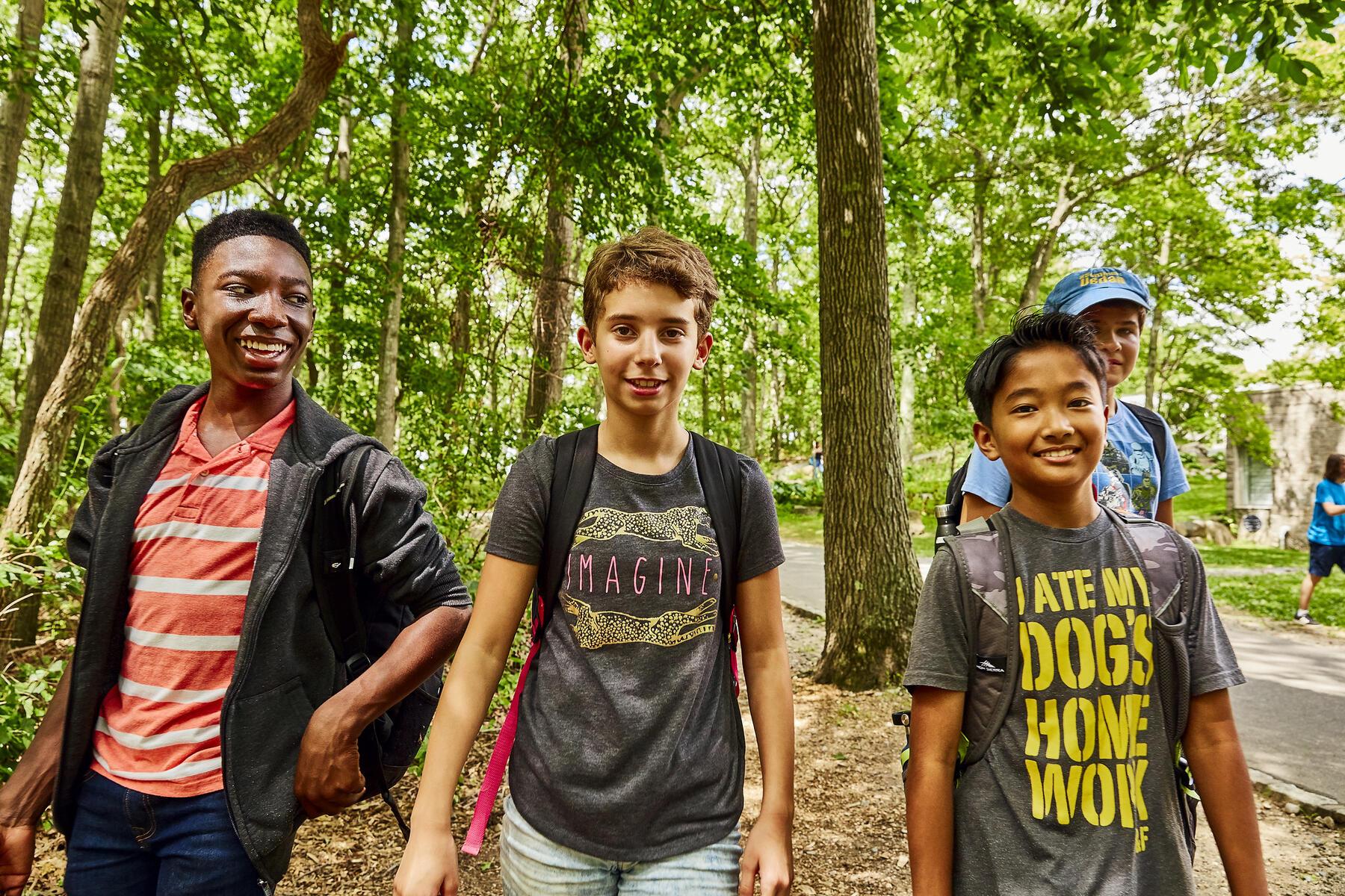 Three kids standing in the woods, smiling