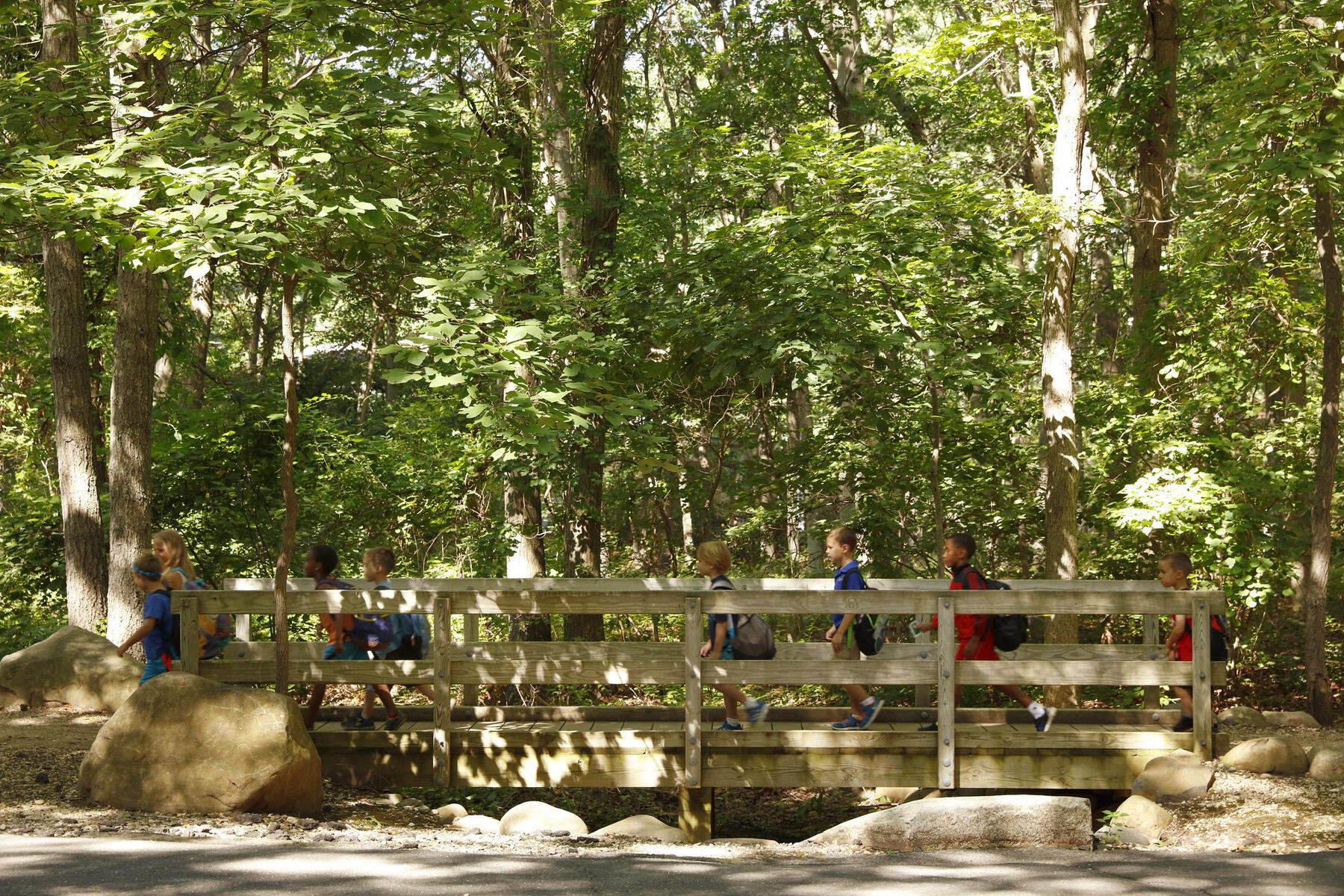 Young kids walking with a counselor over a bridge