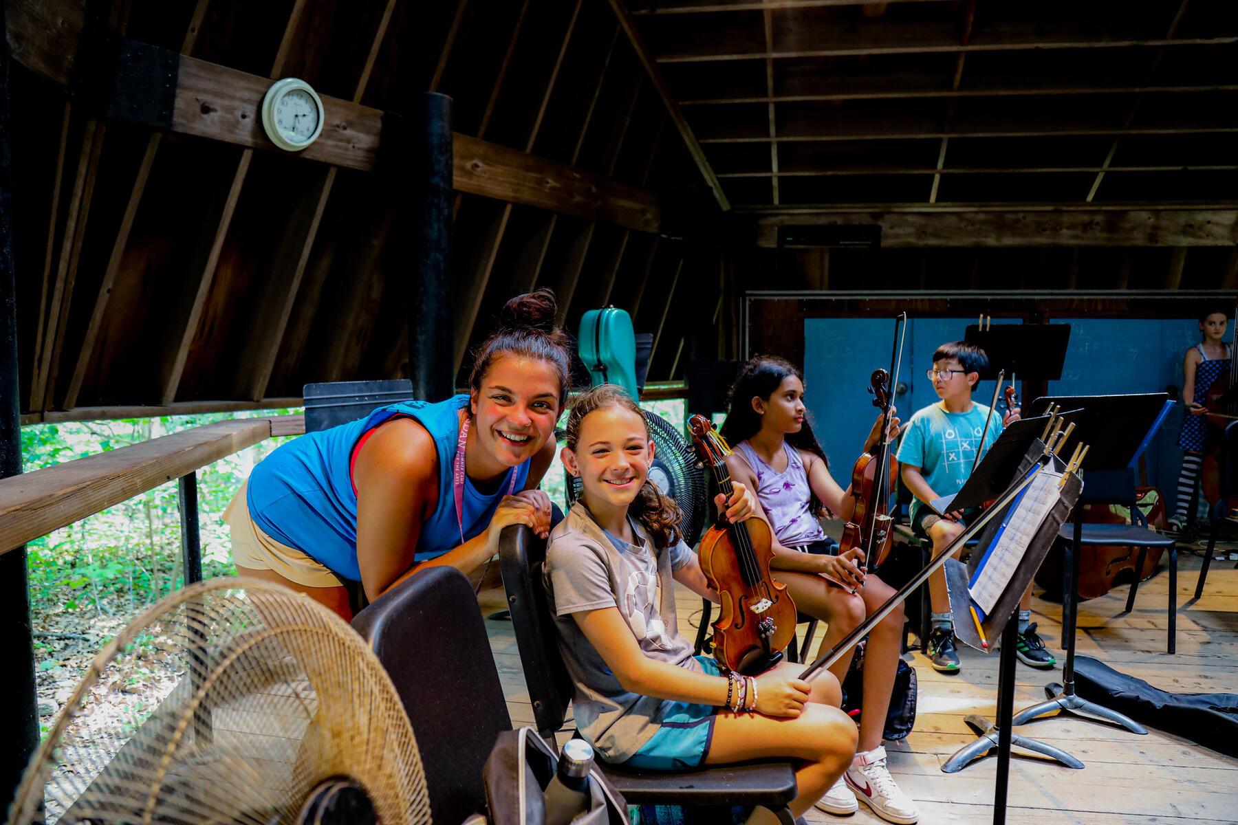 A teacher bending down to pose for a picture with a student holding a violin