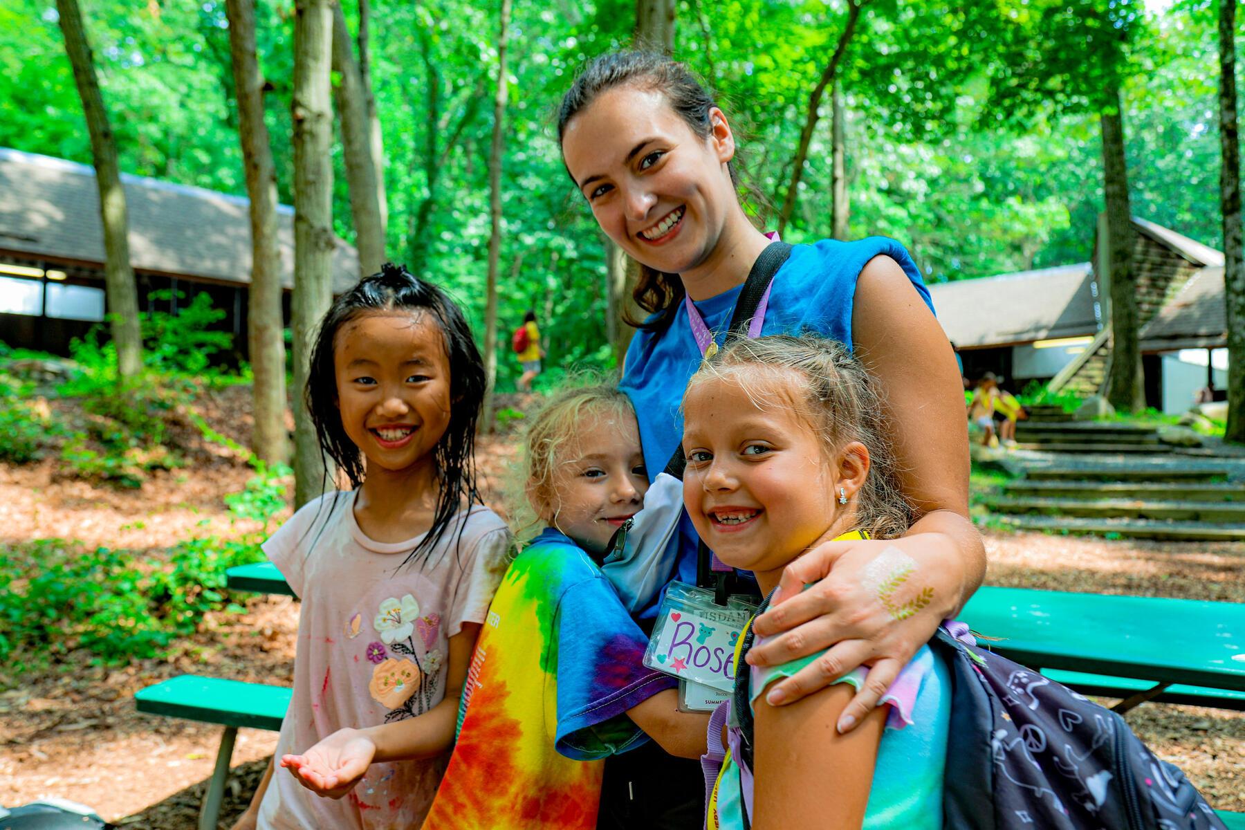 Staff member standing and smiling with a group of children