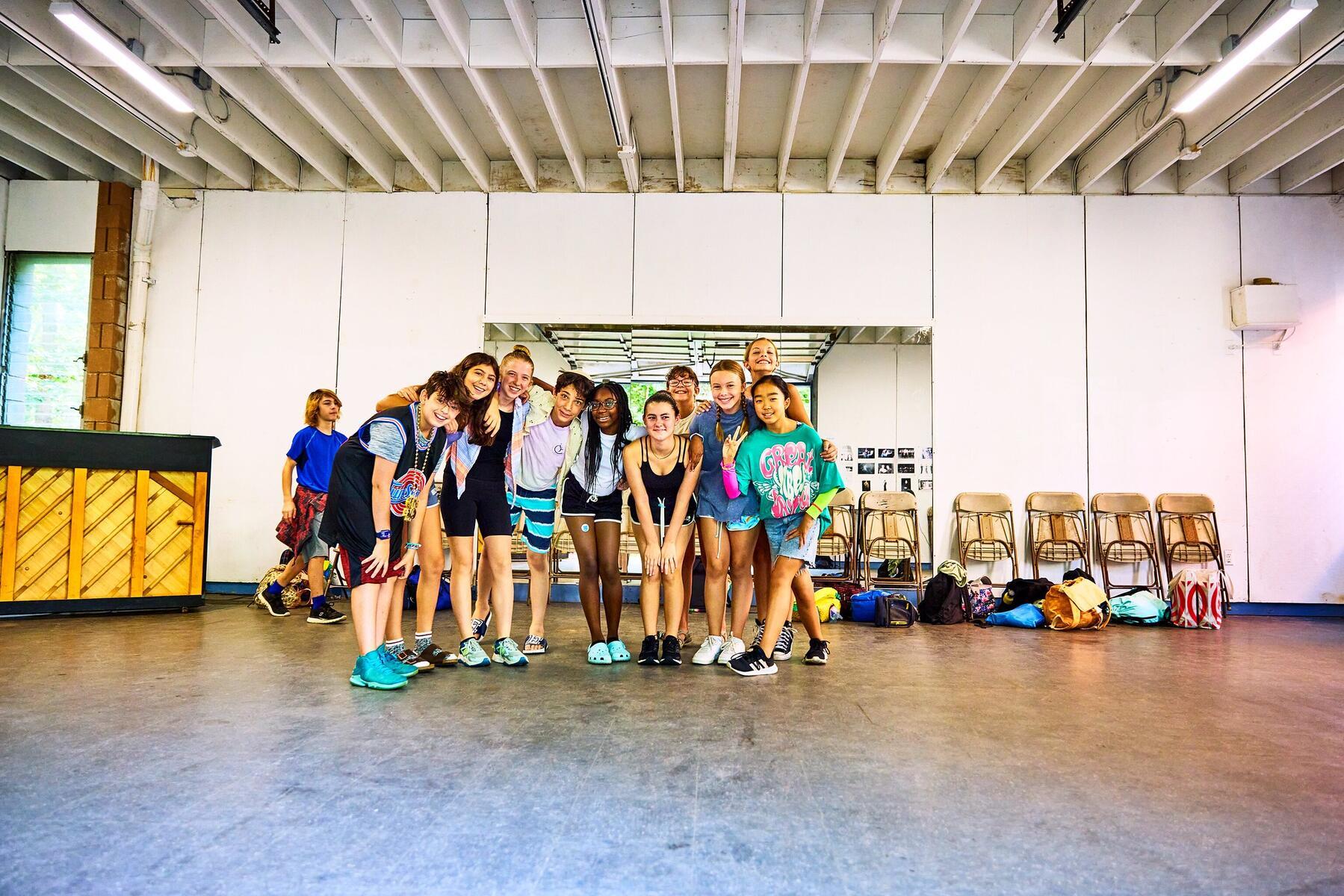 Students standing in theater studio, smiling
