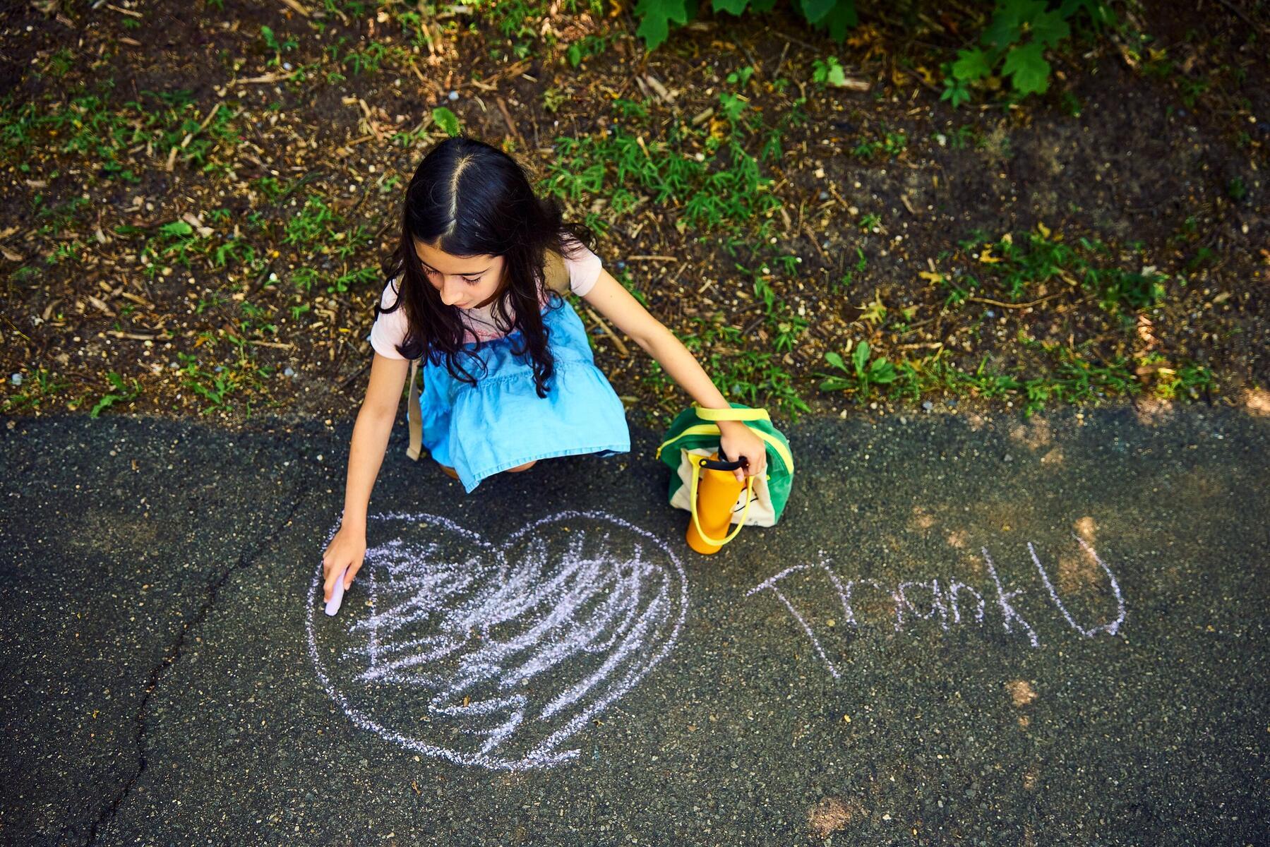 Student drawing "Thank U" in chalk