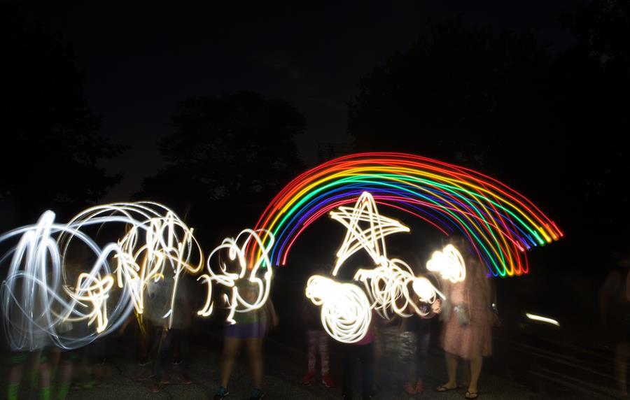 Children in the dark using lights to make shapes with light and motion