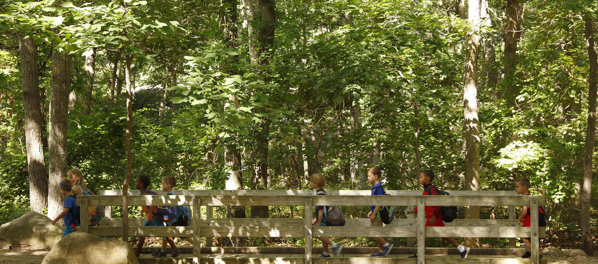 Young kids walking with a counselor over a bridge